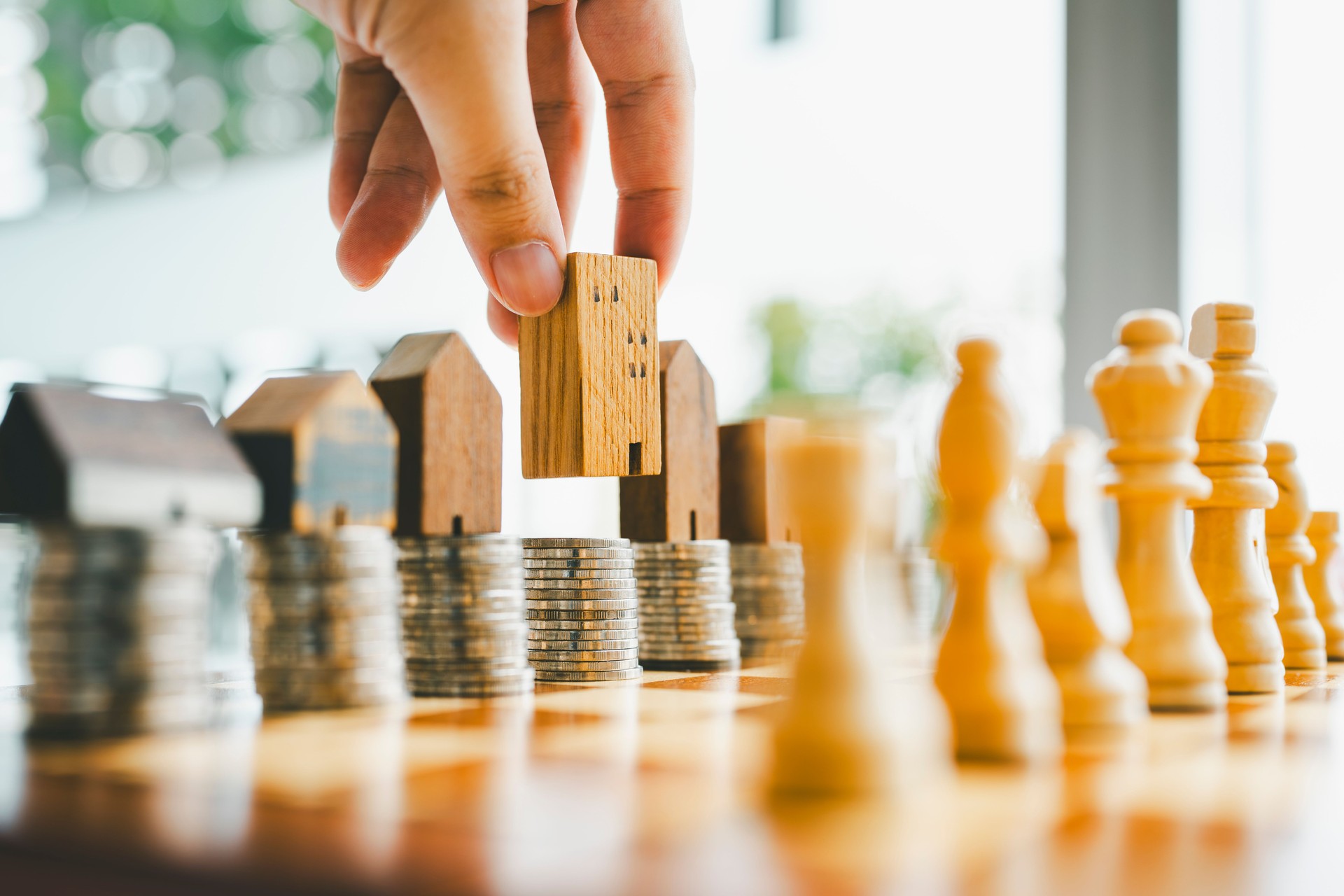 Chess, stack of coins and house models in chess game, competition success play. strategy, management or leadership concept
